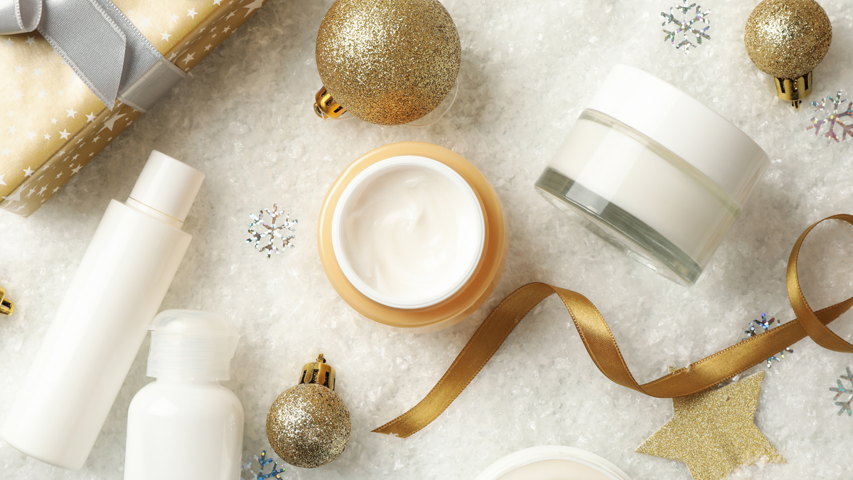 Skincare Produkte liegen auf einem Schneehintergrund daneben Geschenke und Weihnachtskugeln