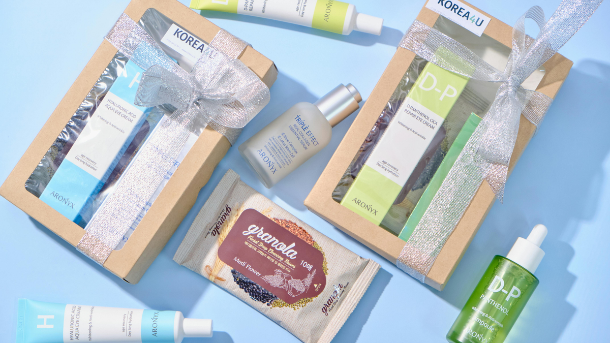 Skincare Produkte in zwei Geschenkboxen und frei liegend auf einer blauen Oberfläche