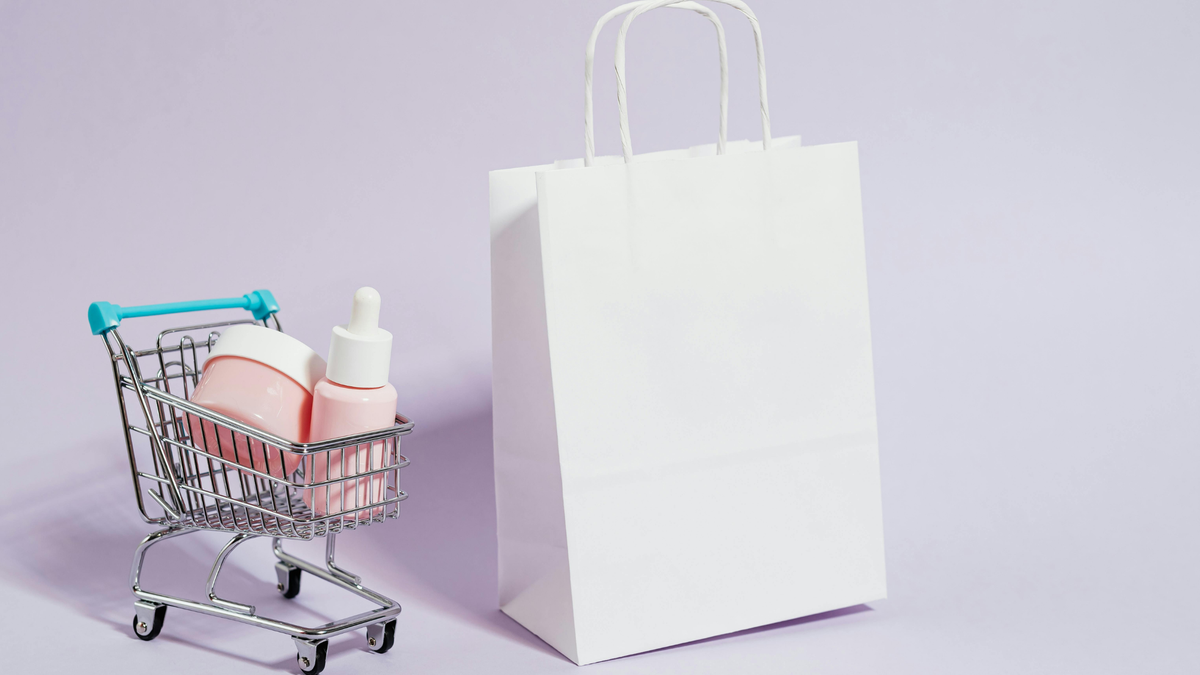 Mini Einkaufskorb mit zwei Skincare Produkten neben einer weißen Tüte