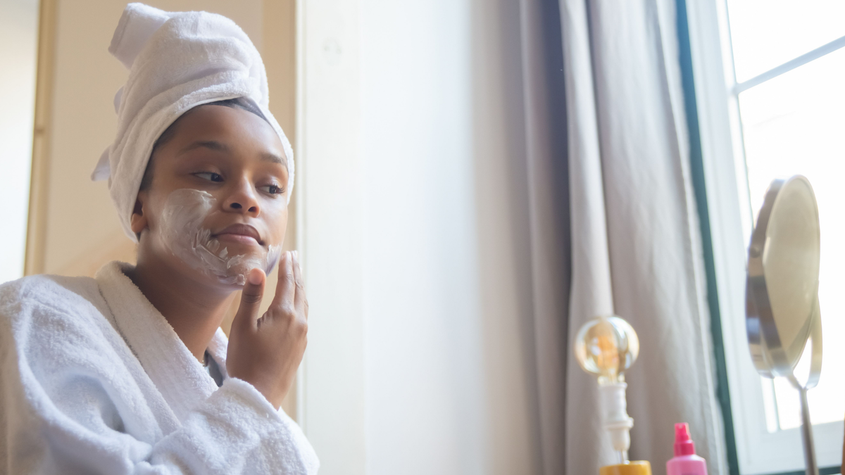 Junge Frau macht ihre Skincare vor einem kleinen Spiegel