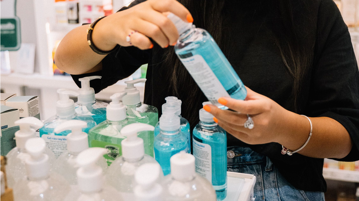 Frau steht vor einem Aufsteller mit Produkten und hält eines in der Hand