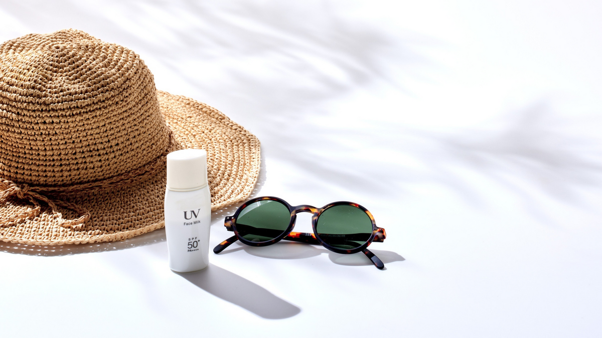 Strohhut, Sonnenbrille und weiße Sonnencreme