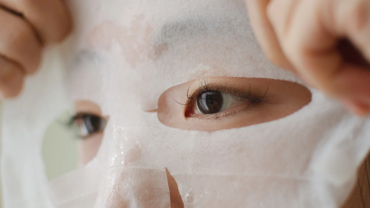 Nahaufnahme der Augen beim Auftragen einer Tuchmaske