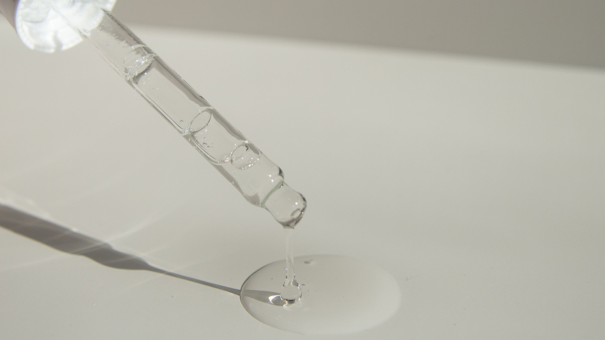 Nahaufnahme Pumpe mit tropfen Serum auf einer Oberfläche