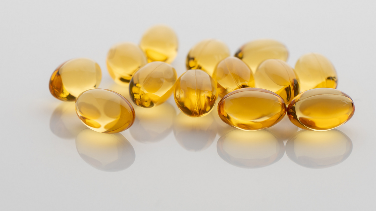 Durchsichtige Vitamin E Kapseln auf weißer Oberfläche 