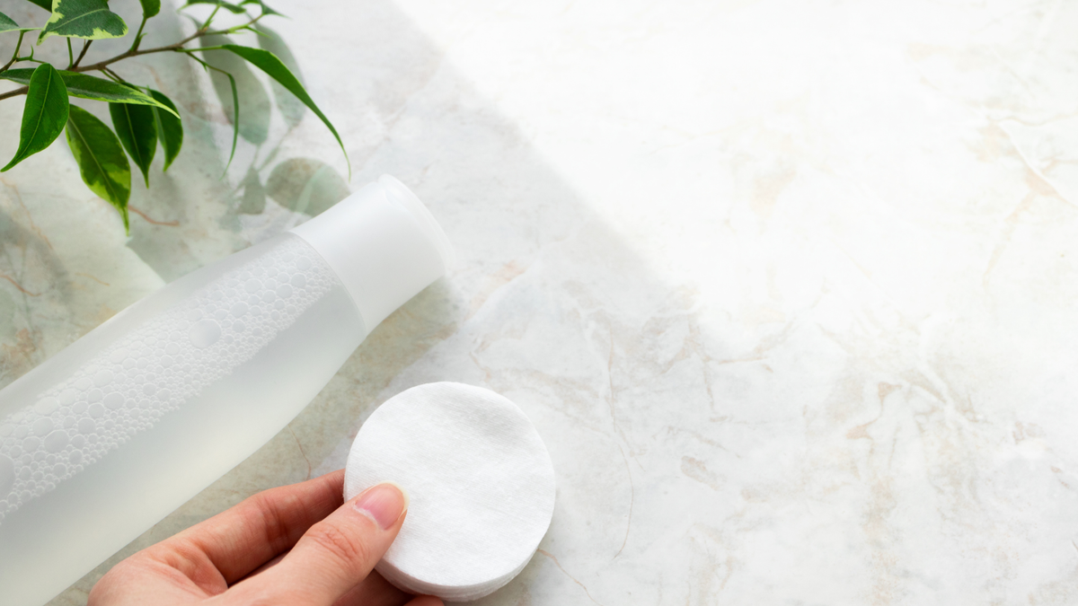In einer Hand sind mehrere Toner Pads und daneben ist eine Flasche mit flüssig Toner