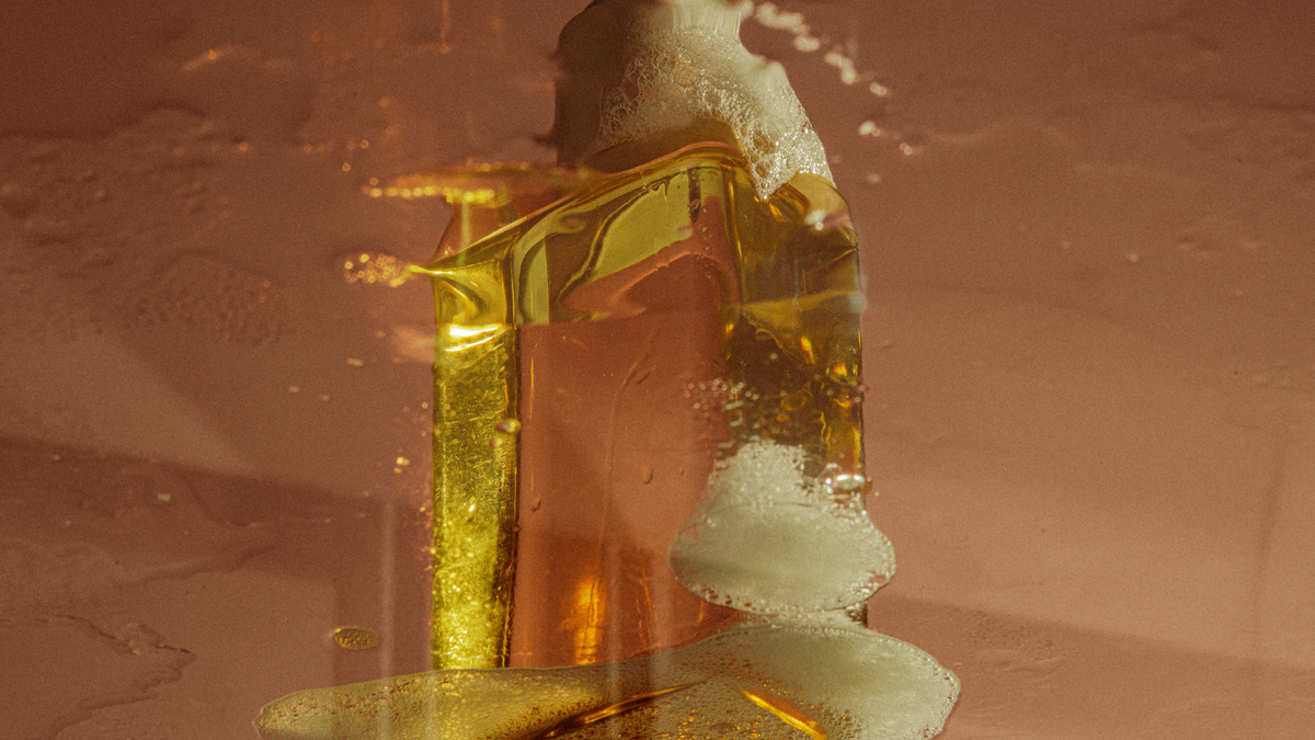 Skincare Wirkstoffe (Schaum, Öl) auf einer rosa/gold farbenen Oberfläche