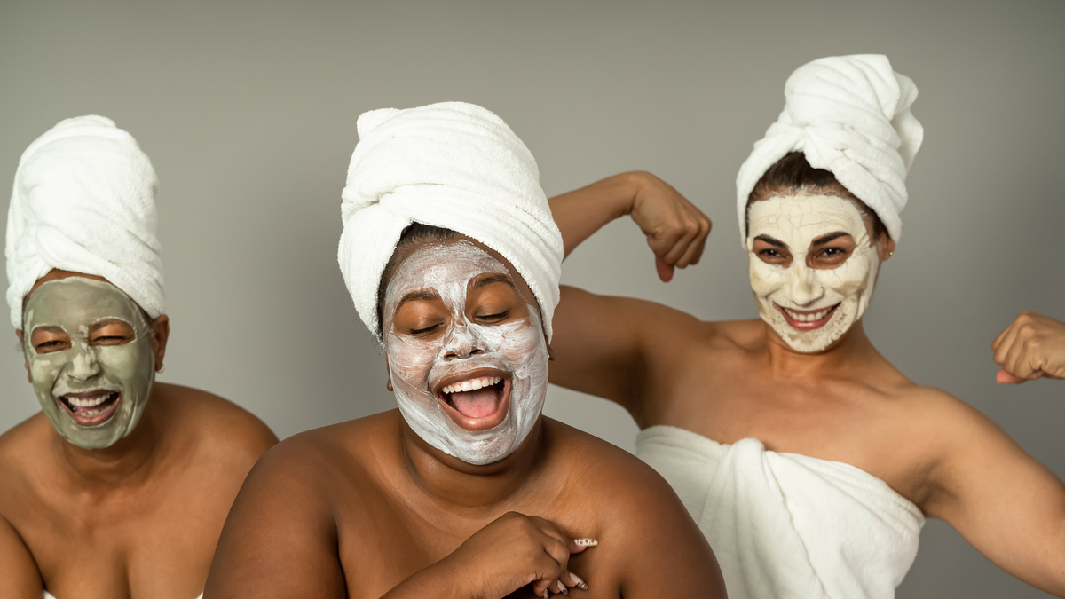 Drei Junge Frauen mit Handtüchern auf dem Kopf und Gesichtsmasken schauen lächelnd in die Kamera